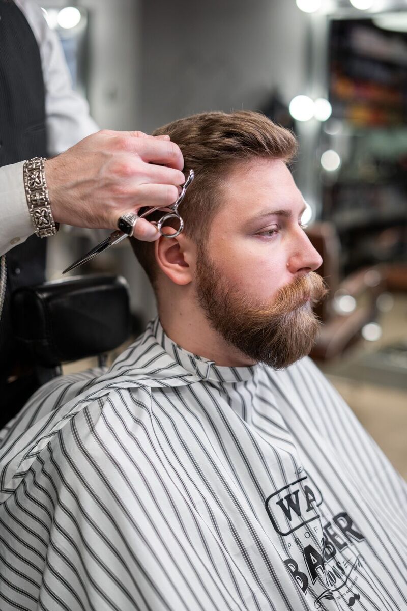 Barber trimming hair at the temple with professional shears