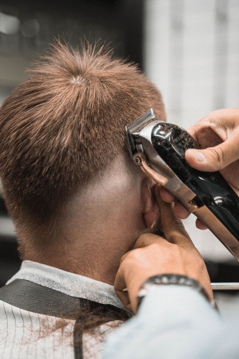 Skin fade being clipped with electric clippers above the ear