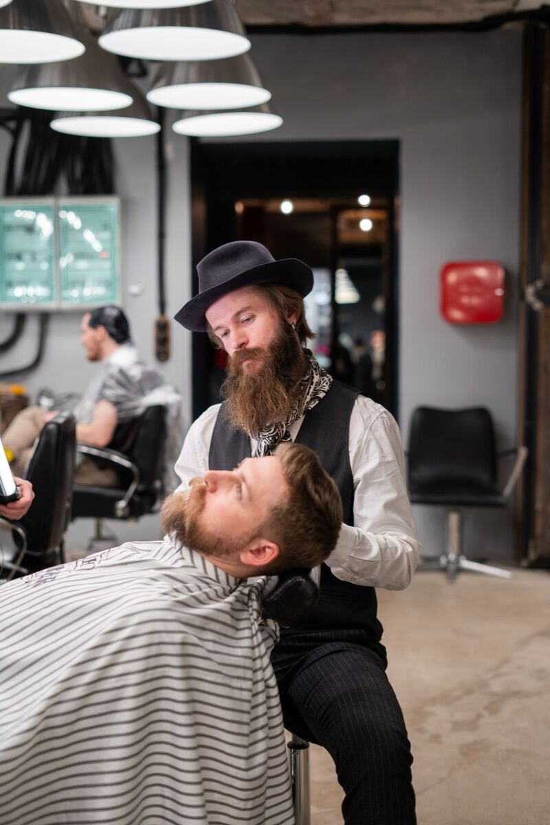 Barber grooming a bearded client reclined in the chair